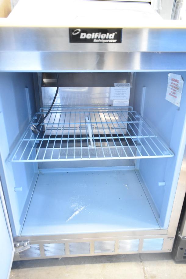 Delfield 4427N-6-DHL-BR2 prep table, stainless steel, interior shelves, model label, warning labels, on casters, good condition.