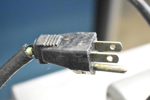 Close-up of a black, slightly worn plug of a countertop waffle cone maker, 120 volts, single phase.