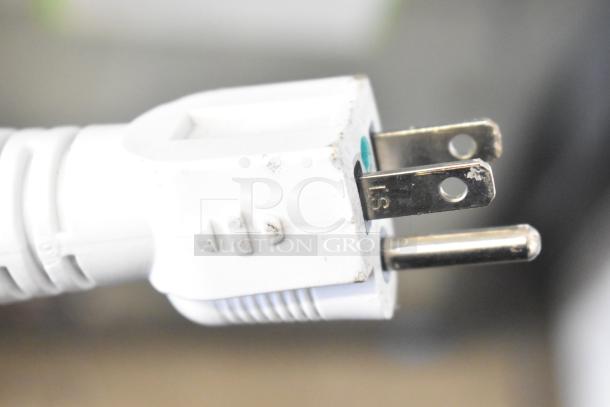 Close-up of a white three-prong power plug, part of the Accucold ARG3PV456 cooler, showing slight wear.