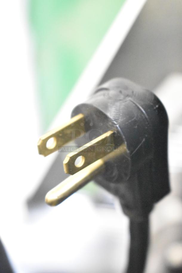 Close-up of a three-prong electrical plug for the Hoshizaki R1A-FSL commercial cooler, showing gold prongs and black casing.