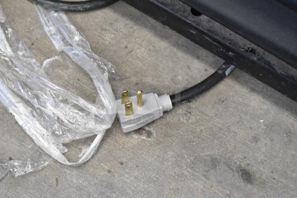 Power cord plug for 2019 True GDM-41SL-48-HC-LD commercial cooler, 115 volts, shown on a concrete floor.