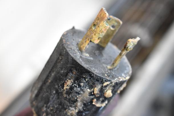 Alt text: Close-up of a damaged electrical plug with corroded prongs.