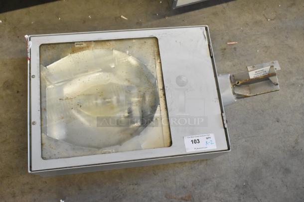 Industrial light fixture in metal casing with glass cover, visible rust and wear. Auction tag notes item 103, quantity 2.