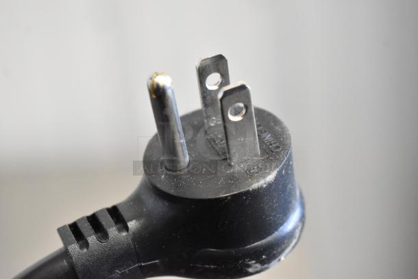 Close-up image of a three-prong electrical plug, compatible with 115 volts, 1 phase.