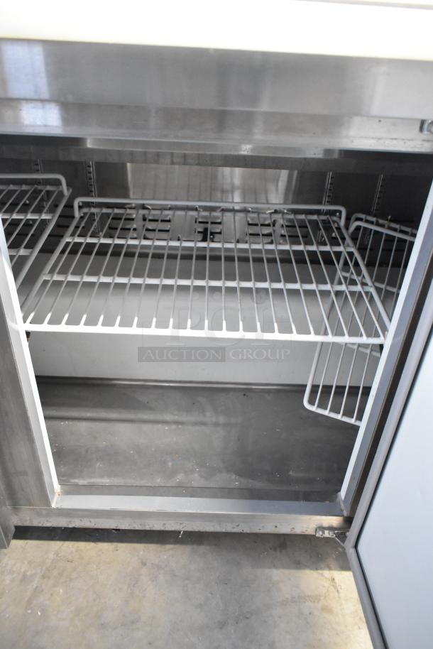 Avantco 178APT71HC Sandwich Salad Prep Table in stainless steel, features commercial casters, shown with wire shelving inside.