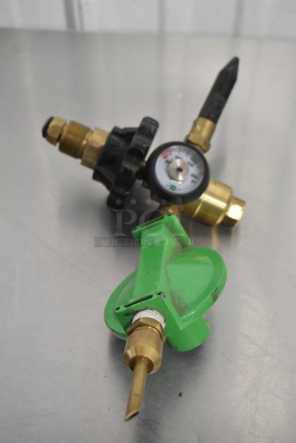 Three brand new scratch and dent connectors, including a handle and two brass fittings with gauge, on a metal surface.