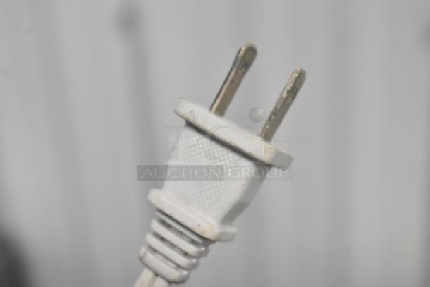 Close-up of a white power plug, part of the Food Saver Vac750 Vacuum Bag Sealer set, condition unknown.