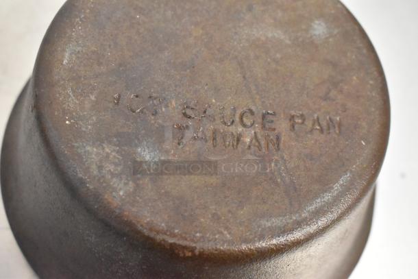 Rustic metal pan with "1QT SAUCE PAN" and "TAIWAN" marking. Worn condition. Accompanied by a black poly bin and rack.