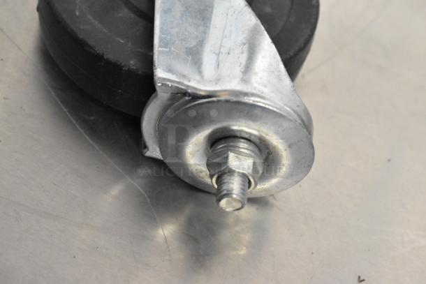 Close-up of a commercial caster with a metal frame and rubber wheel, showcasing bolt and nut detail.