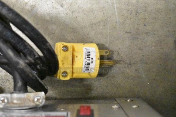 Close-up of yellow electrical plug with barcode label connected to Fetco CBS-2132-XTS coffee machine wiring.