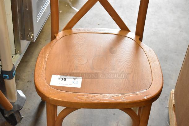 Set of three wooden dining-height chairs with X-back design, in good condition. Label indicates auction lot 136, quantity 3.
