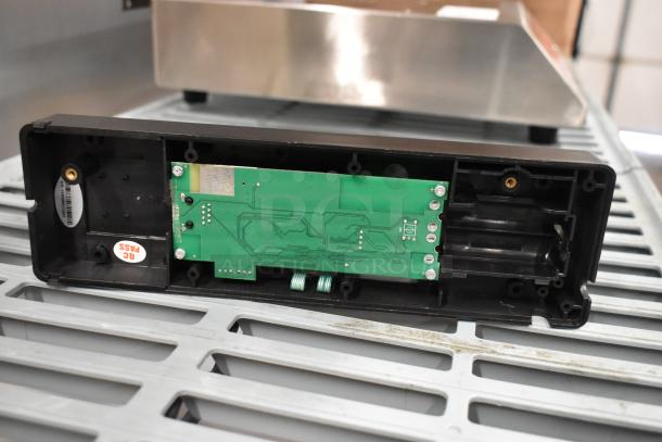 Black electronic control panel, featuring an exposed green circuit board. Includes a visible "QC PASS" label, indicating quality check completion. Appears in good condition with mounting points and connectors intact.