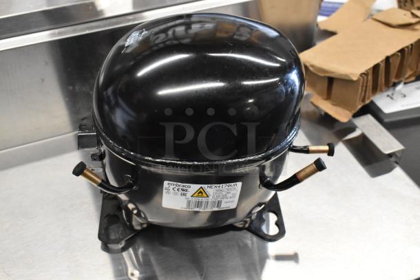 Brand new Embraco NEX4170UA compressor with minor scratches. 115-127 volts, 1 phase. Labels indicate model and specs.
