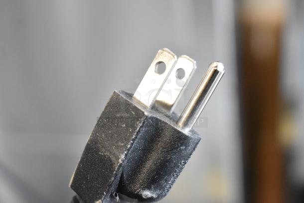 Close-up of a standard three-prong plug, associated with the 2025 Bunn MHG coffee grinder.