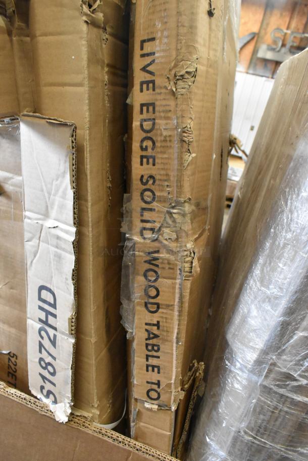 Boxes labeled "LIVE EDGE SOLID WOOD TABLE TOP" and "51872HD" showing shipping wear, indicating new scratch and dent items.