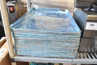 Stack of 25 brand new Vollrath 5315 and Choice 18"x26" aluminum bun pans on shelf, wrapped in blue protective film.
