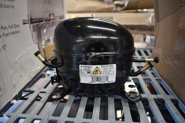 BRAND NEW Embraco EMC3134U compressor for various models; 115V, R-290. Scratch and dent condition. Visible label details specs.