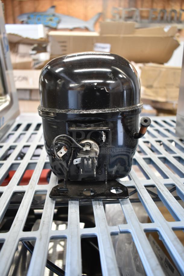 BRAND NEW Cubigel NUT55NR compressor, scratch and dent, compatible with Avantco models, shown on metal grid.