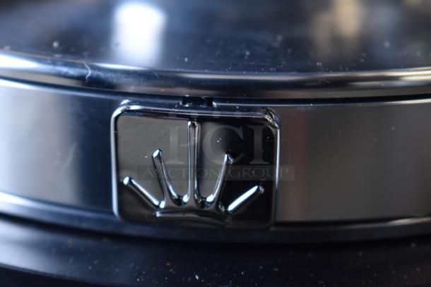 Close-up of Mahlkonig E65W espresso grinder's chrome logo on a sleek black surface, showing fine detail on the brand emblem.