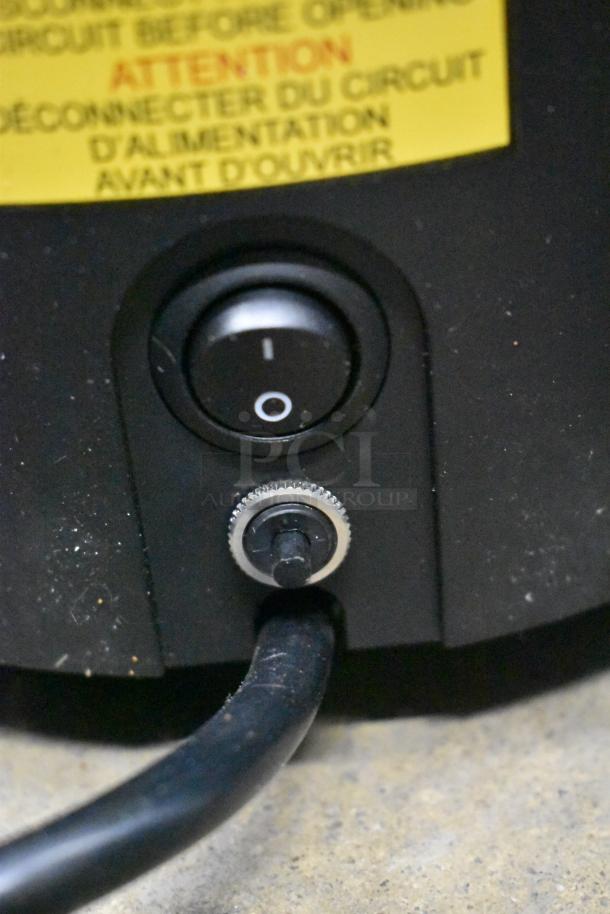 Close-up of a black switch on the Mahlkonig E65W espresso grinder, showing power settings and a yellow warning label in French, indicating caution before operation.