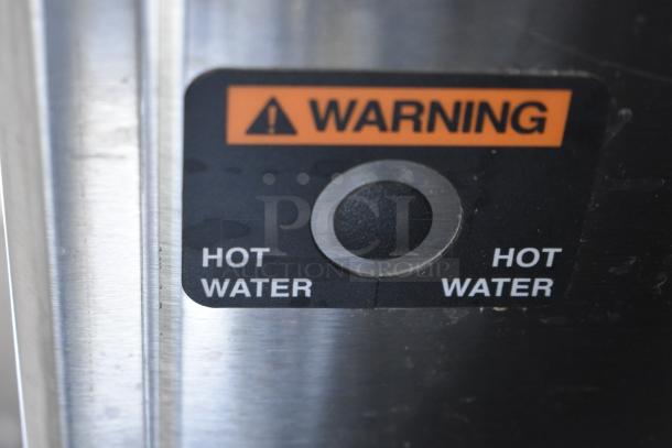 Stainless steel panel with a "Warning: Hot Water" label on the 2025 Bunn ICB-DV coffee brewer.