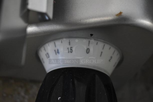 Avantco 177SL312 meat slicer dial close-up, showing scratch on metal. Dial marked 0-15, indicating slice thickness.