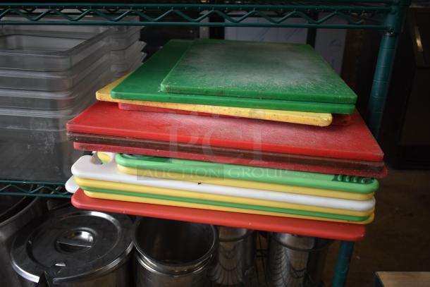 Two-tier lot includes various cutting boards in multiple colors and stainless steel cylindrical bins, used condition.