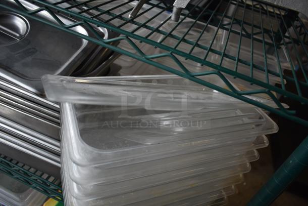 Assorted stainless steel and poly drop-in bins in used condition, stacked on metal shelving. Suitable for storage or organization.