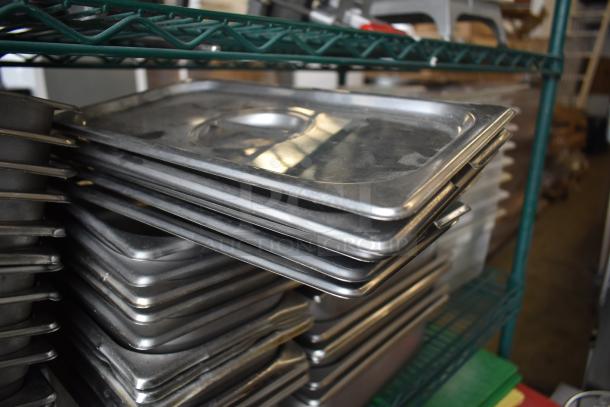 Stack of stainless steel drop-in bins on a green metal shelf, showing slight wear, part of varied auction lot.