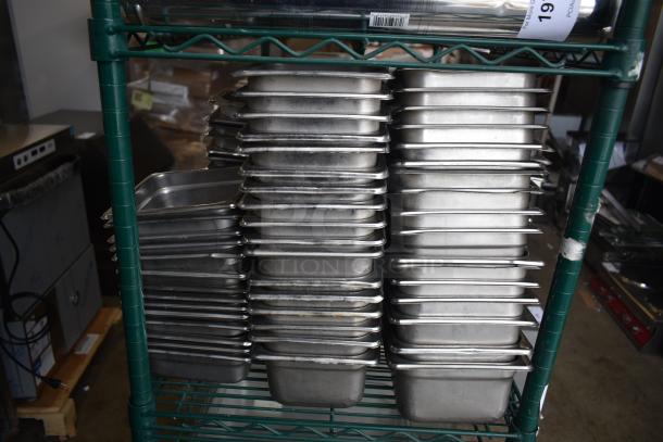 Tiered lot of stainless steel and poly drop-in bins on a green metal rack. Used condition, varying sizes. Auction item.