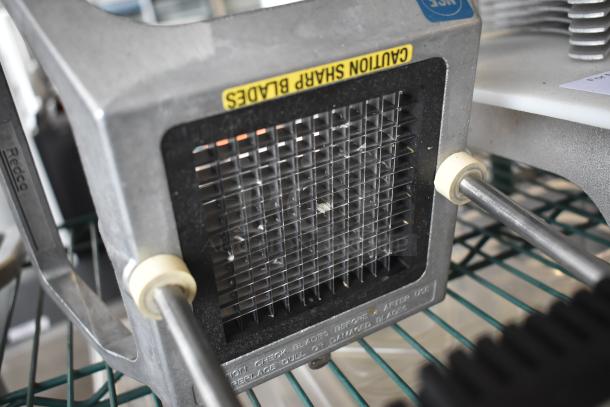 Industrial vegetable cutter with grid blades, "Caution Sharp Blades" label, metal frame, in gently used condition.
