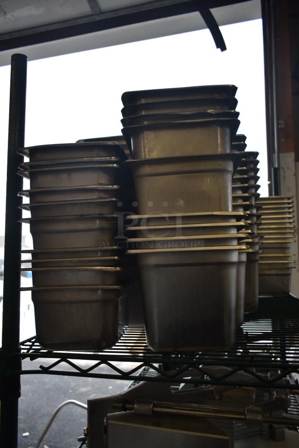 Stack of stainless steel and poly drop-in bins on metal shelf. Used condition, suitable for storage or industrial use.