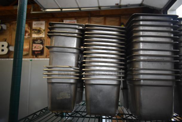 Stacked stainless steel and poly drop-in bins on display. Industrial setting, minor wear visible. Part of tiered lot sale.