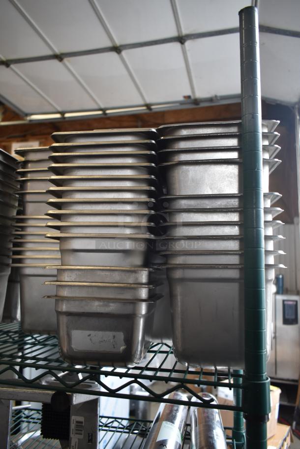 Stack of stainless steel and poly drop-in bins on a wire rack, showing slight wear, ideal for commercial kitchen use.