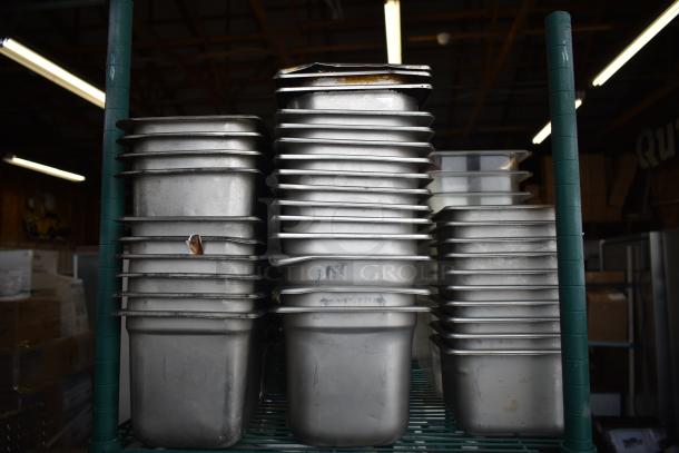 Tiered lot of stainless steel and poly drop-in bins stacked on a shelf. Used, varying sizes. Ideal for storage or kitchen use.
