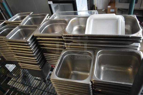 Stack of stainless steel and poly drop-in bins in various sizes, used condition, on wire shelving.