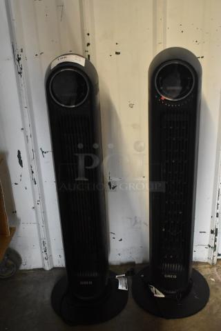 Two Dreo DR-HTFOOT tower fans, black, 120 volts, single-phase, in good condition with visible control displays.