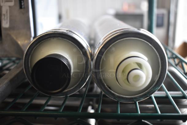 Two Pentair Everpure EV9612 water filter cartridges on metal shelf, showing top view, pristine condition.