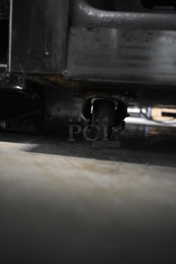 Delfield commercial cooler on caster, 115V, 1 phase. Close-up of caster, showing sturdy metal construction, good condition.