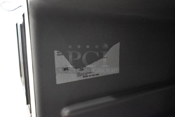 Delfield undercounter cooler label, NSF certified, made in USA, indicates commercial refrigeration. Visible wear on label.