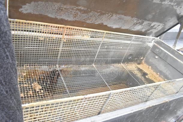 Commercial floor-style washing tank with metallic mesh, showing signs of rust and wear. Ideal for industrial cleaning needs.