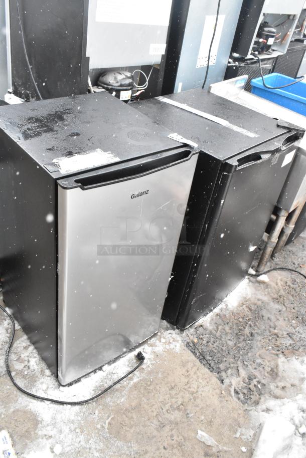 Two mini coolers including Galanz GLR33MS1E02 and Kismile BD-88B-E, 120 Volts, 1 Phase, steel and black finish, outdoor setting.