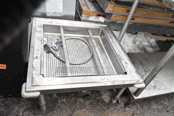 Stainless steel bin with straining insert on commercial casters, snowy surface, includes coiled hose, durable for heavy use.