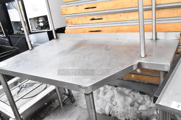 Stainless steel table with under and over shelf, industrial design, sturdy condition, suitable for kitchen or workshop.