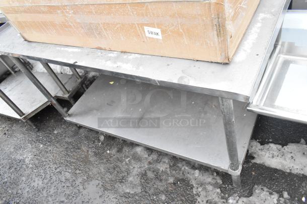 Stainless steel table with sturdy under shelf, showing minor wear. Ideal for commercial kitchen use.