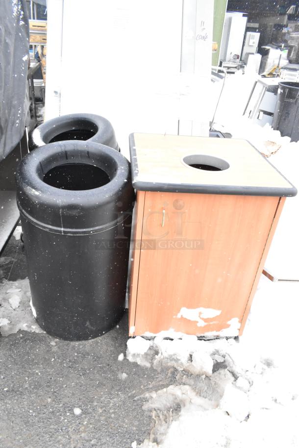 Three trash can shells: one wooden, two black plastic, used condition, snow around base. Ideal for outdoor use.