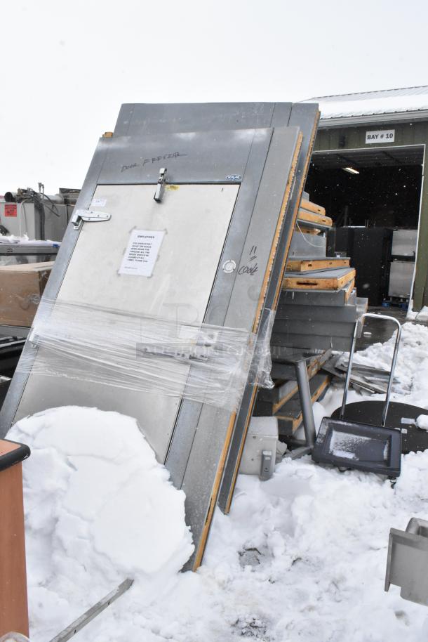 Norlake walk-in box parts, laid flat in snow, includes doors and panels. Features compressor info on attached papers.