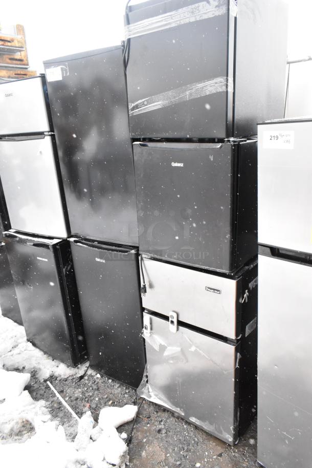 Nine Galanz mini coolers, models GLR33MBKE23 and GLR31TS1E02, black and silver, 120 volts, stacked outdoors.