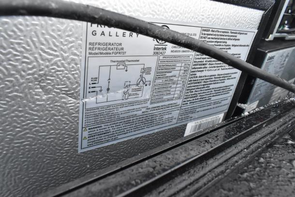 Labels on the back of a Frigidaire Gallery refrigerator indicate model FGFR727 and safety warnings.