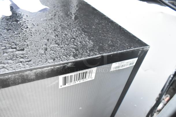 Alt text: Close-up of mini cooler corner with barcode labels, featuring Haier and Galanz models. Black exterior under light moisture.